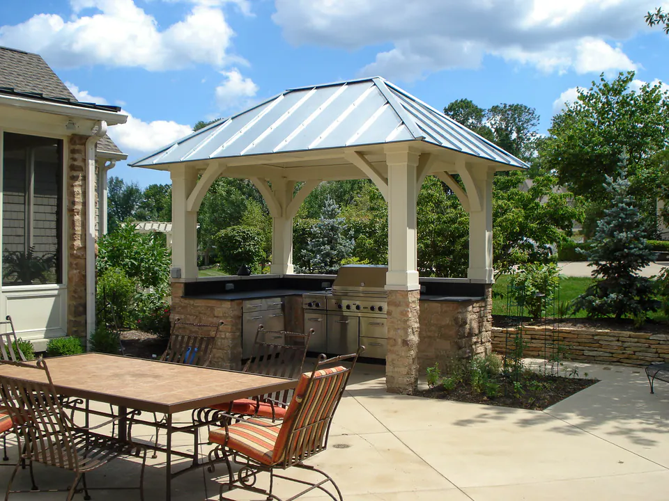 Outdoor kitchen and dining area beneath a metal-roof pavilion